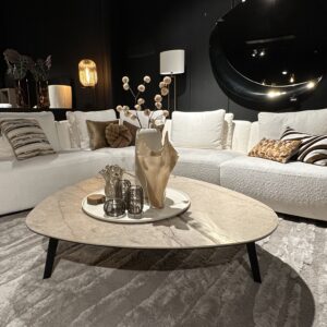 Luxe woonkamer met witte modulaire zitgroep, rond marmeren salontafel en verfijnde gouden en zwarte accessoires